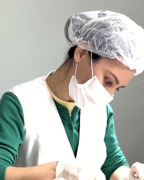 Dra. Roberta Sayuri, de touca, máscara e luvas, realizando uma aplicação na face