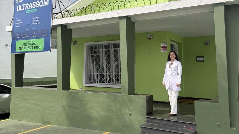 Dra. Roberta Sayuri, médica, de jaleco branco, na entrada do CEMID, em Guaianases, Zona Leste de São Paulo