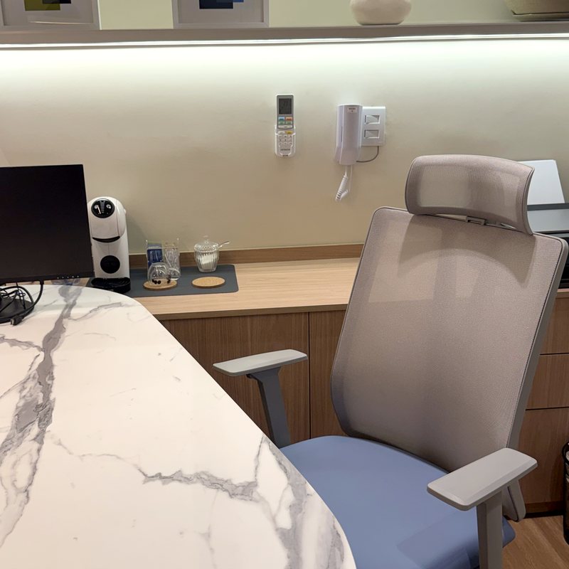 Sala de consulta com mesa de mármore, cadeira e computador, onde a avaliação é feita com calma